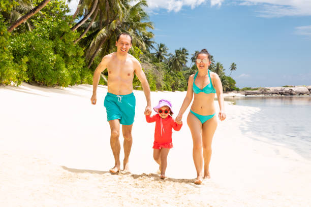 istock Smiling Young Family Walking On The Beach 1150346385