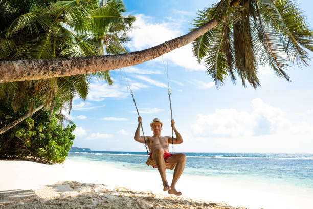 istock Young Man Enjoying Swinging On The Beach 1150346429