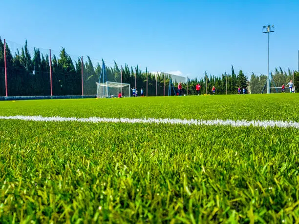 Photo of Image of artificial grass in the foreground and background of children playing soccer
