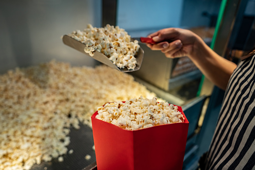 Close-up on a woman serving popcorn at a concession stand at the cinema
