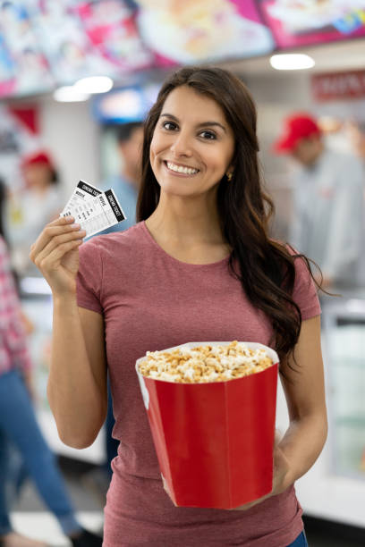 happy woman at the cinema holding movie tickets - ticket movie theater movie movie ticket imagens e fotografias de stock