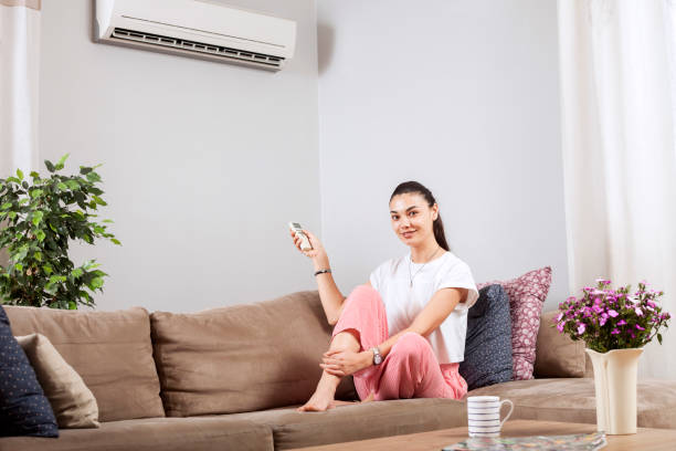 istock woman using remote control of air conditioner 1150347133