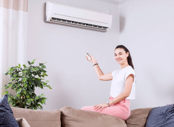 istock woman using remote control of air conditioner 1150347789