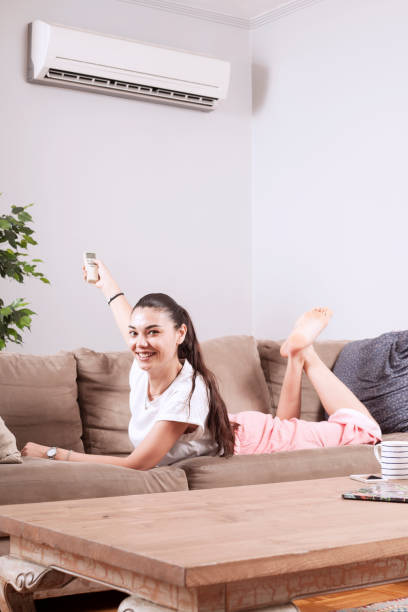 istock woman using remote control of air conditioner 1150347799