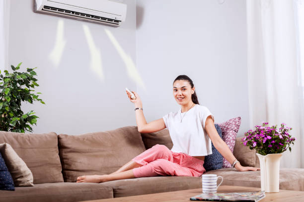 istock woman using remote control of air conditioner 1150351523
