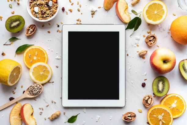 gesunder super-food-und technologie-hintergrund, digitale tablet-computer-apps zum kochen diät-ernährungsplan, frische frucht-granola-samen auf weißem bio-tisch, gesundheitsentgiftung, top-ansicht mockup-bildschirm - granola breakfast dieting food stock-fotos und bilder