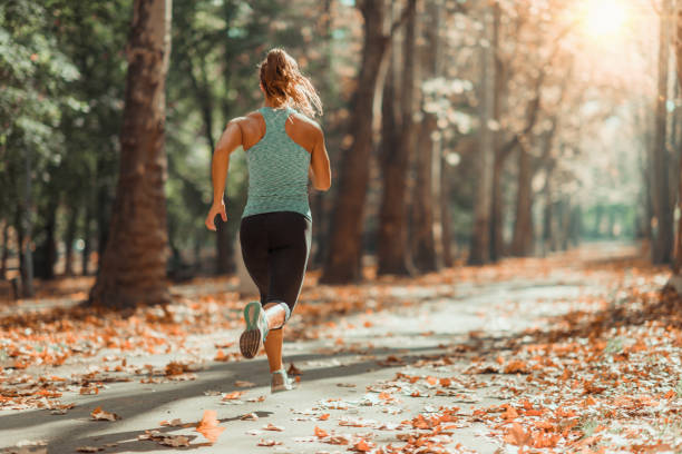 woman jogging outdoors in the fall - autumn women park forest imagens e fotografias de stock