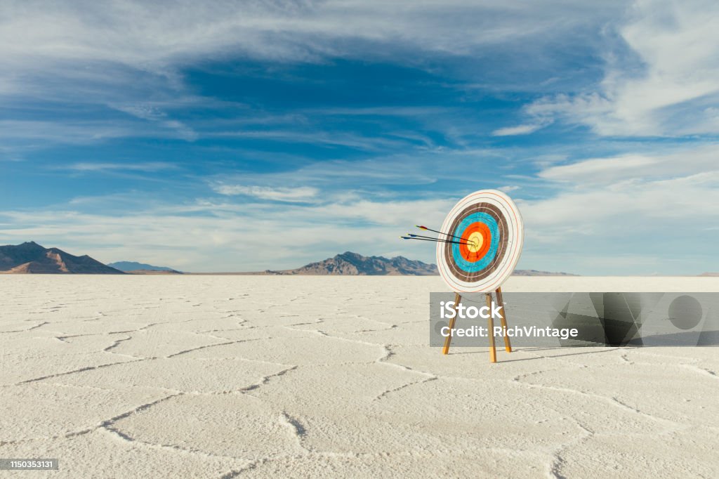 Arrows in Bulls-Eye of the Target Arrows are in the center of the target, hitting their mark in the bulls-eye. Precision is paramount in target shooting. This image symbolizes preparation, determination and accuracy it takes to reach a goal. Image taken on the salt flats of Utah, USA. Sports Target Stock Photo