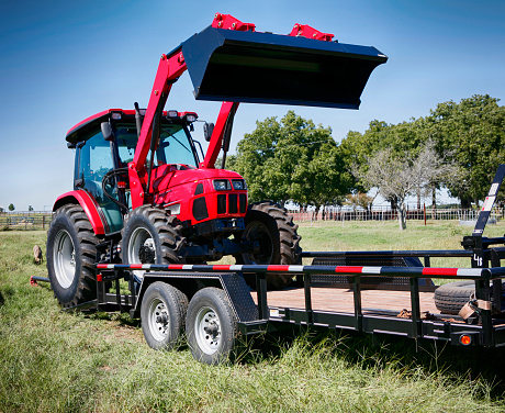 Texas farming: delivering/towing a large red tractor.