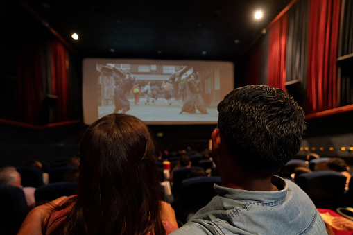 Happy couple watching a movie at the cinema - entertainment concepts **Image on the screen is ours**