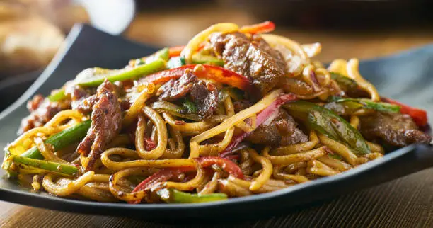 asian stir fried noodles with beef peppers and onions panorama shot with selective focus
