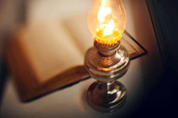 istock Vintage kerosene lamp burning and open book 1150357118