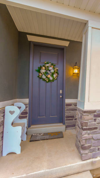 clear vertical gray front door on the facade of a home decorated with bauble and flower wreath - doormat door christmas holiday imagens e fotografias de stock