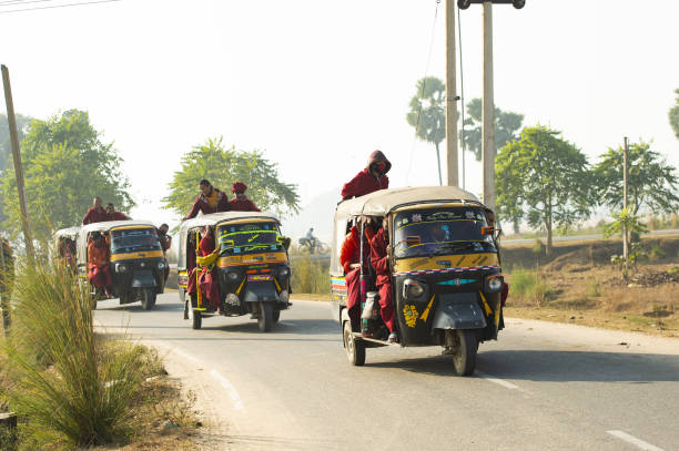 um grupo de monges budistas está em um auto rickshaw (tuc tuc) em bodh gaya. bodh gaya é um local religioso da índia, no estado indiano de bihar. - accident taxi driving tourist - fotografias e filmes do acervo