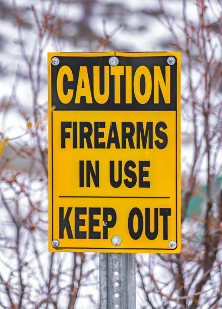 istock Close up of a yellow sign that reads Caution Firearms In Use Keep Out 1150372721