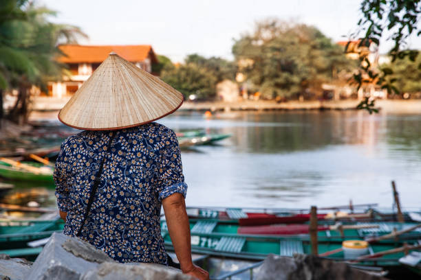 istock Vietnamese woman rowing a boat in river 1150374500