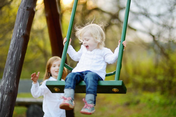 istock Two little sisters having fun on a swing 1150377918