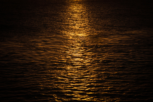 Sunset reflection on the surface of the ocean. Beautiful golden light rays