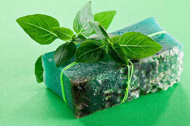 Piece of natural soap with basil on a green background.