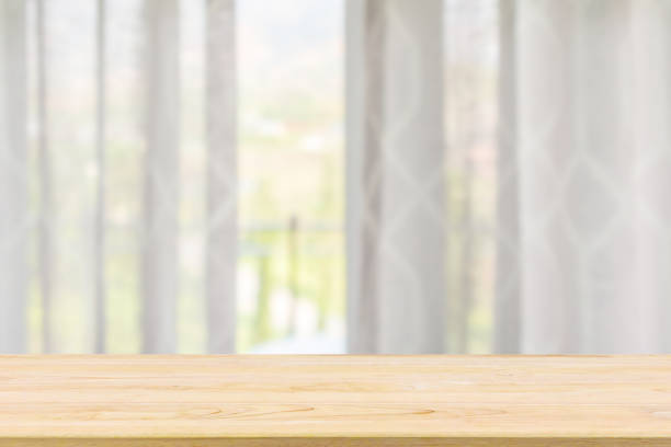 istock Empty wood table top with window curtain abstract blur background for product display 1150384491