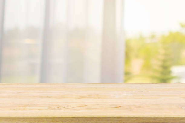istock Empty wood table top with window curtain abstract blur background for product display 1150384493