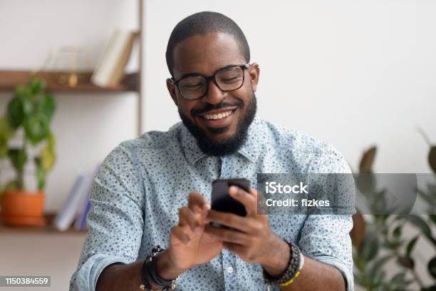 Happy African American Businessman Using Phone Mobile Apps At Workplace Stock Photo - Download Image Now