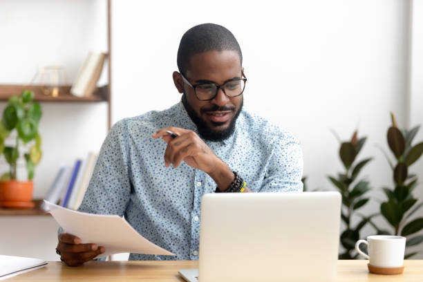istock Focused african american businessman working with laptop documents in office 1150384561
