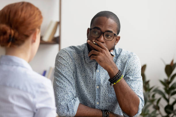 dubbiosa hr africana parlando con il candidato caucasico al colloquio di lavoro - complaining foto e immagini stock