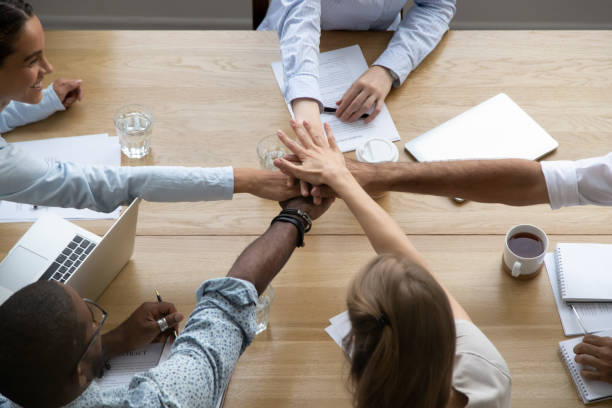 istock Team people stacking hands together over table engaged in teambuilding 1150384608