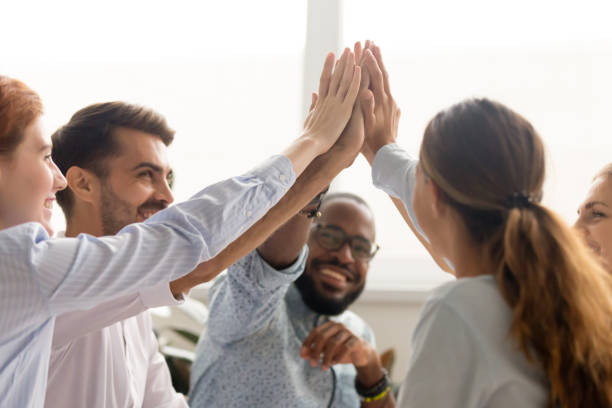 Multiracial associate business people group join hands give high five Multiracial associate business people group teammates hands give high five together promising unity as dream team concept, corporate success, teambuilding and loyalty, support in teamwork, coaching high five stock pictures, royalty-free photos & images