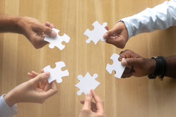 istock Close up top view of hands holding connecting jigsaw puzzle 1150384637