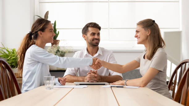 Happy female business partners handshake sign contracts with lawyer mediation Happy female business partners shake hands sign two contracts with lawyer mediation at meeting, smiling businesswomen handshake make legal partnership deal after successful negotiations with mediator mediation photos stock pictures, royalty-free photos & images