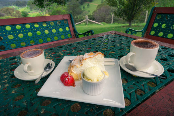 Two cups of coffee with lemon meringue cake, strawberry and scoop of ice cream
