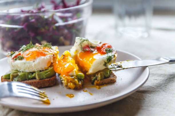 istock Breakfast served of two toasts with avocado, fried eggs with vegetables and herbs on a rustic tablecloth background. View from above. Healthy and nutritious food concept. 1150385333