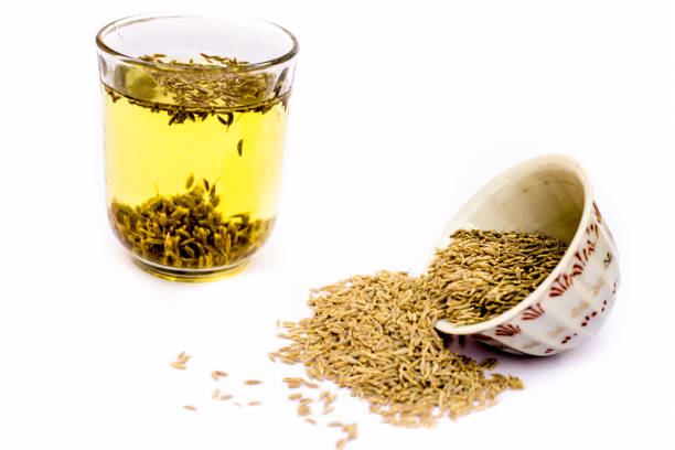 Herbal detoxifying drink isolated on white i.e. Jeera water with some raw organic cumin in a glass bowl. stock photo