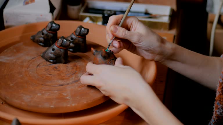 Professional potter painting ceramic souvenir penny whistle in pottery workshop