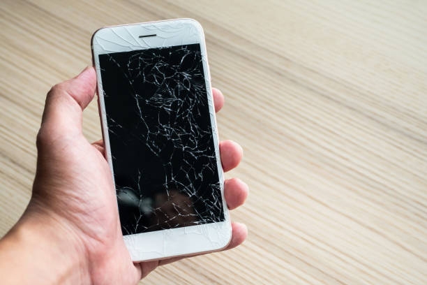 istock Hand holding mobile phone with broken glass screen 1150390150