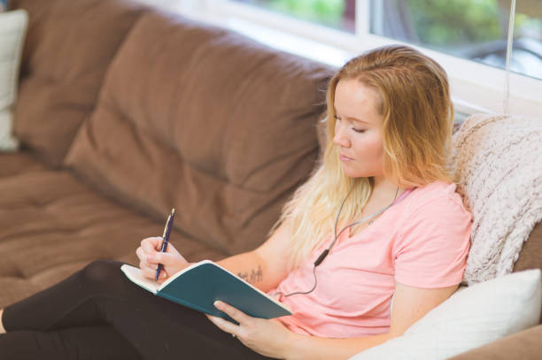istock Young woman journaling on the couch 1150390199
