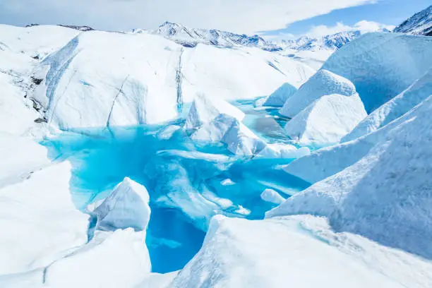 Deep blue water of partially frozen supraglacial lake on the Matanuska Glacier in Alaska.