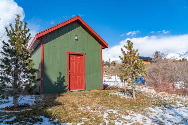 istock Small storage shed on grassy terrain with trees and powdery snow 1150392162