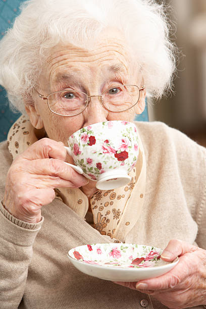 Old lady sipping from a teacup with floral pattern