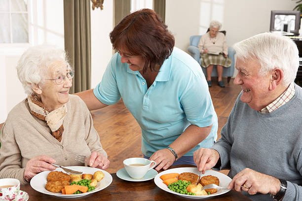 par sênior sendo servida refeição pelo prestador de - senior adult nursing home eating home interior imagens e fotografias de stock