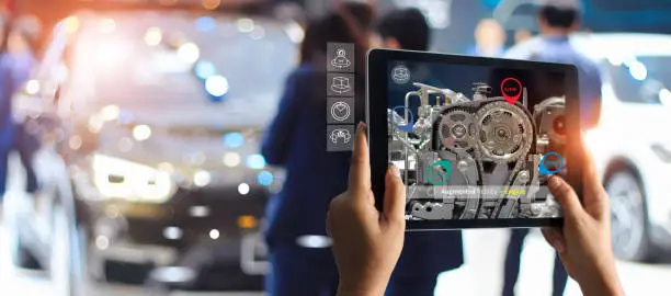 Augmented reality concept. AR. Industrial 4.0 , Hand of engineer holding tablet using virtual AR service application to check the work of electric machine on car showroom background