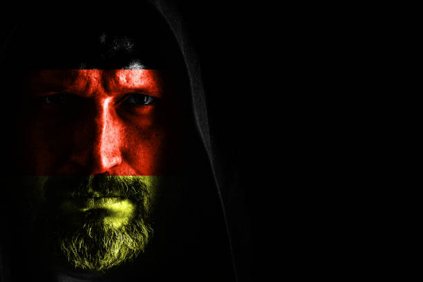 istock Brutal man with a gray beard in the hood with sharp shadows on a black background. Copy space. 1150402872