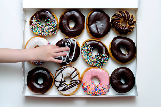 Donut Box with Young Girl's Hand Grabbing One stock photo