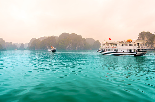 Beautiful Tourist cruise ship floating among limestone rocks at Ha Long Bay. This is the UNESCO World Heritage Site, it is a beautiful natural wonder in northern Vietnam