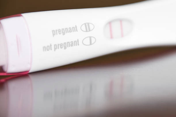 Positive Pregnancy Test Close-Up on a Brown Wooden Table stock photo