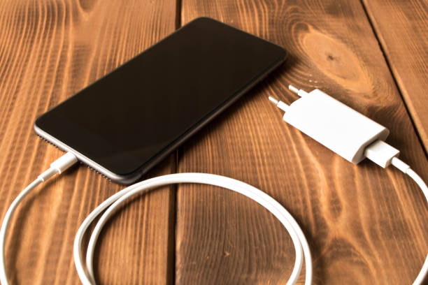 istock Smartphone on charge . On the  wooden table . Close up. 1150410790
