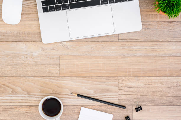 istock The office desk flat lay view with laptop, mouse, tree, black clip, coffee cup, notebook, pencil on wood texture background. 1150413358