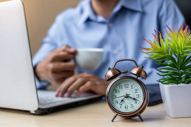 istock Close up alarm clock with young Businessman using laptop analysis marketing plan and drinking coffee in the morning. Business, Finance and lifestyle concepts 1150415203